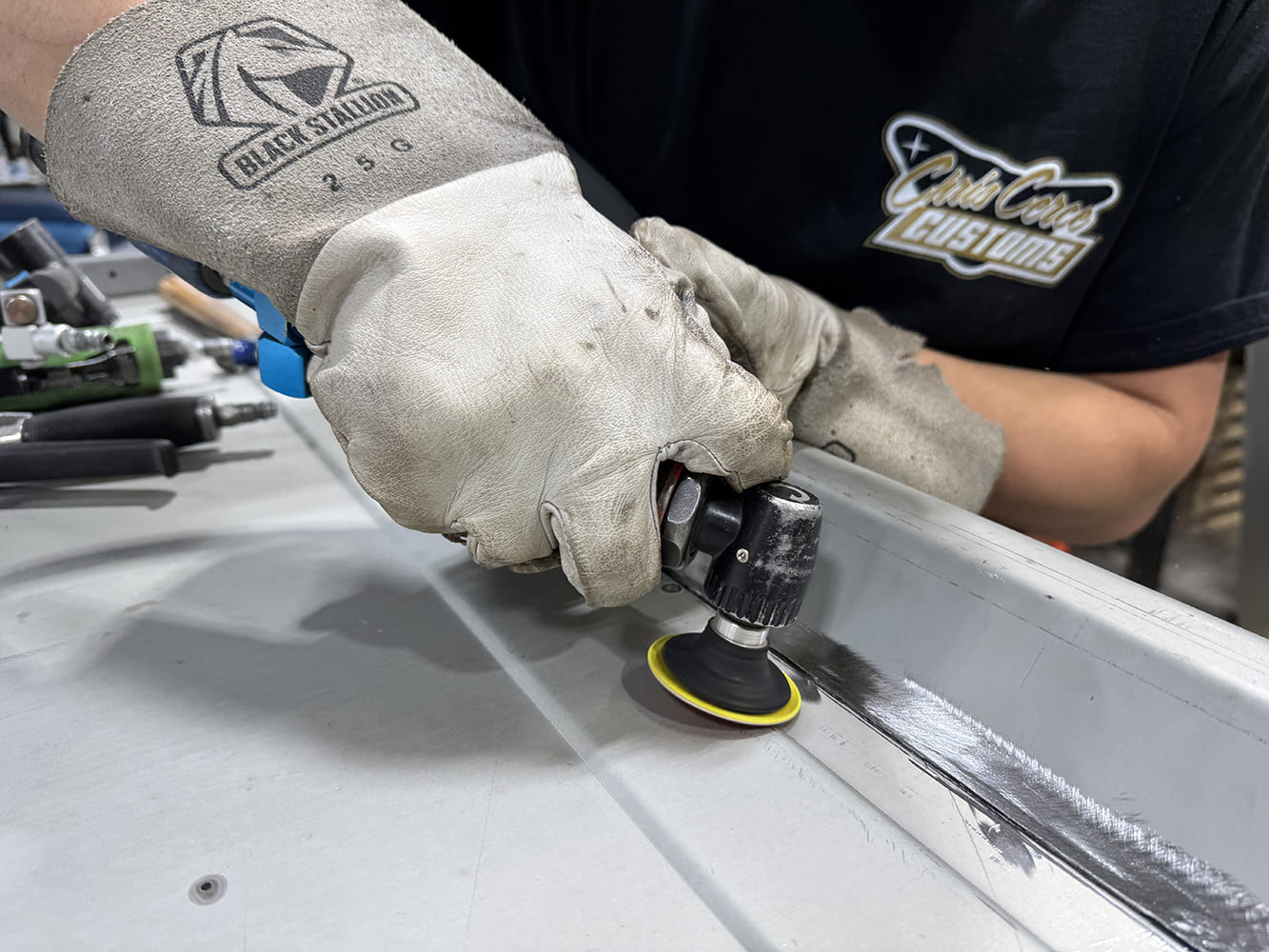09 Detail grinding weld area small pneumatic grinder yellowblack disc polished grind body tools in background Club Carce shirt