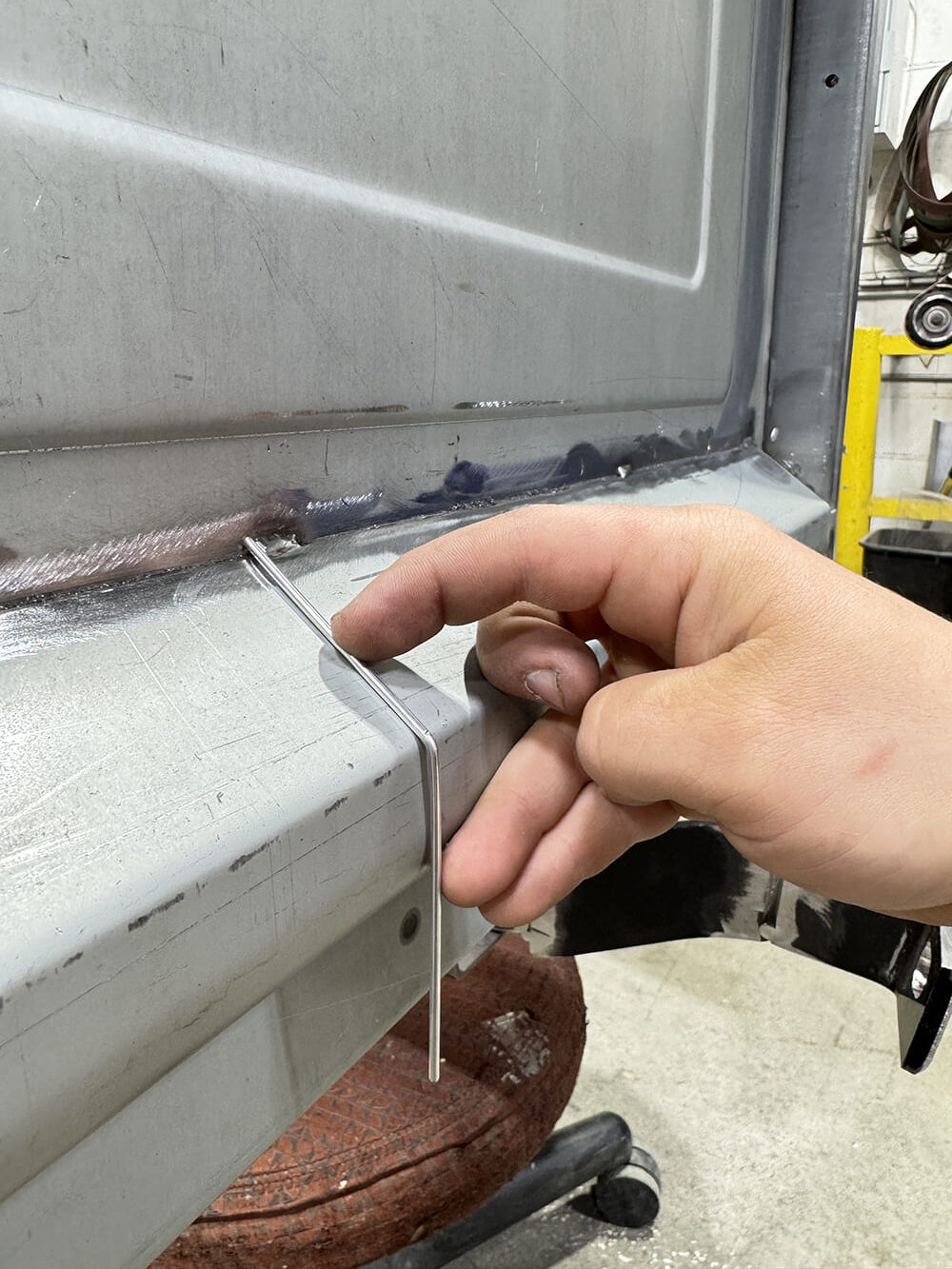 16 Bent wire gauge at tailgate edge weld seam hand close up