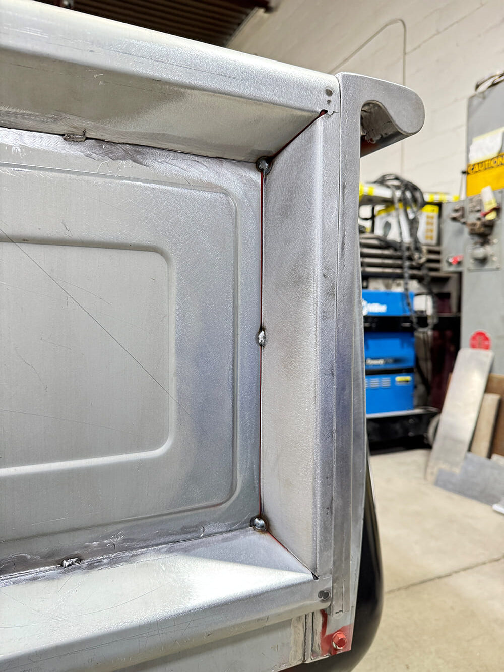 26 Finished inner corner panel welds blended smooth minor grind marks Miller machine in background