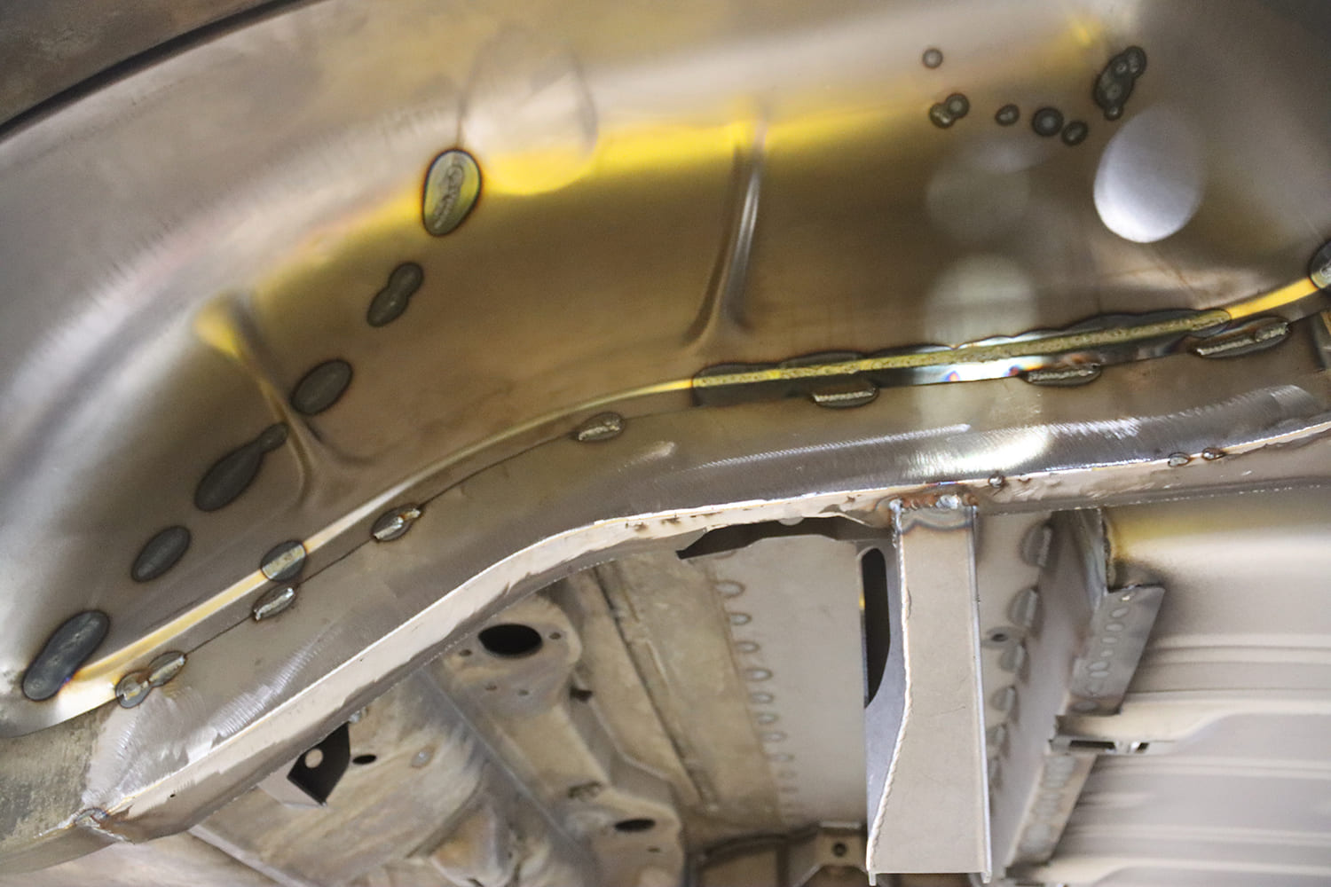 004 1963 Chevy Nova Clean plug welds secure Detroit Speed brackets along the inner rear wheel tub