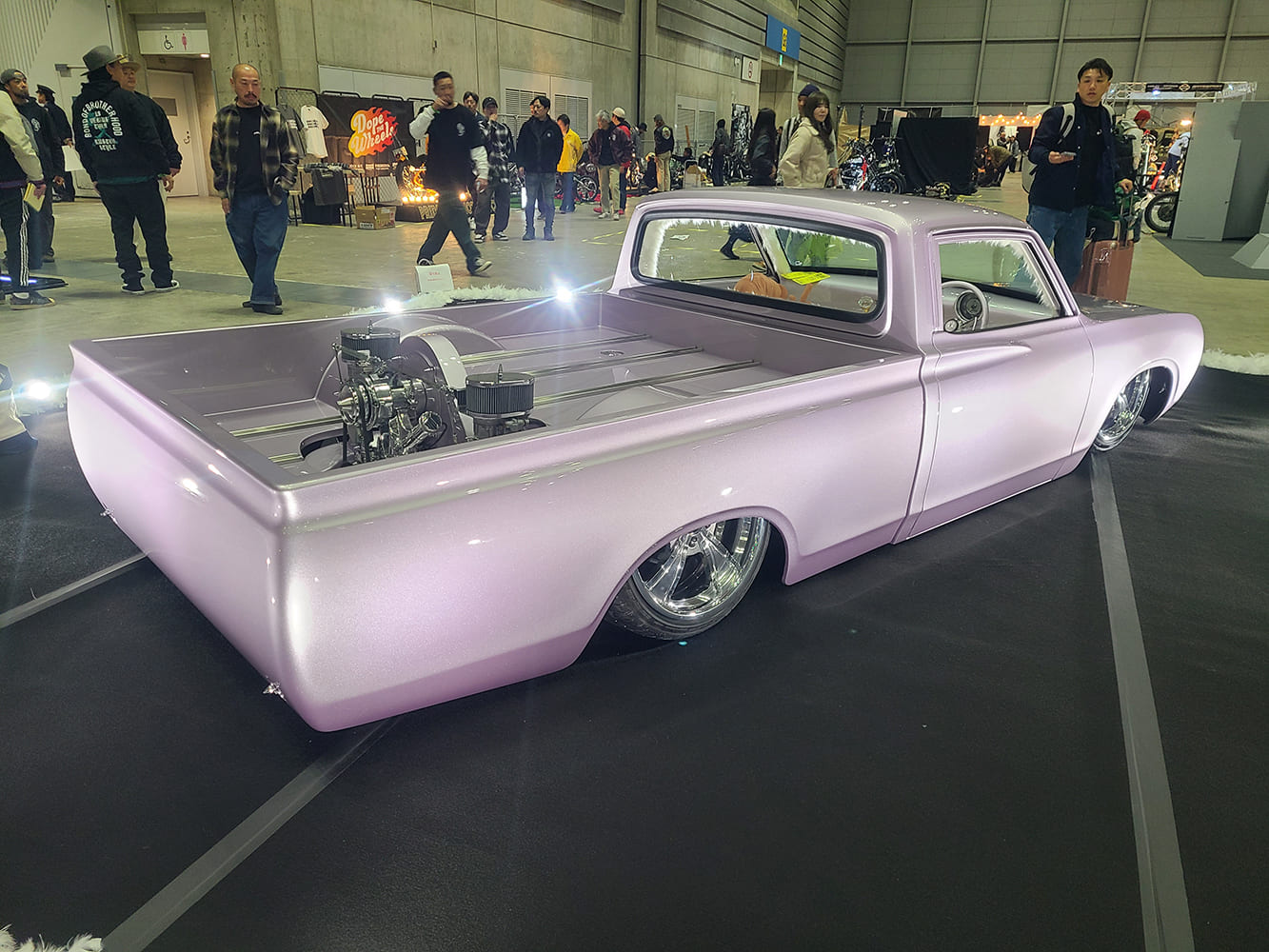 Lavender pearl slammed custom pickup truck rear three quarter view indoor car show display with polished engine setup