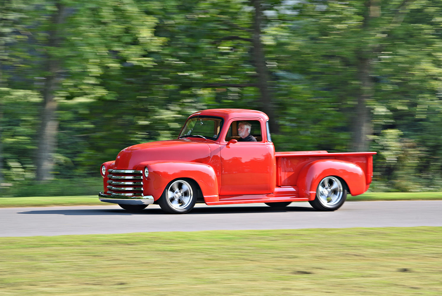 Chevrolet 3100 custom red pickup truck rolling driving shot motion blur lowered hot rod