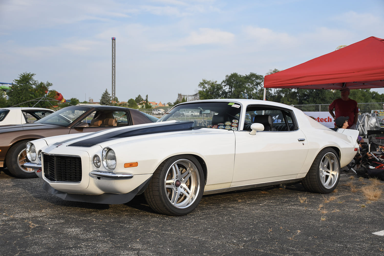 Front three-quarter view of a clean white split-bumper second-gen Chevrolet Camaro RS with a black-striped cowl hood and modern forged split-spoke wheels.