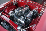 Detailed high-angle view of a candy apple red 1969 Chevy Camaro engine bay showcasing a custom supercharged LS V8 engine with a polished Holley EFI intake manifold, billet accessories, and aluminum radiator.