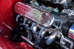 Close-up detail of a high-performance engine in a candy red 1969 Chevy Camaro featuring polished vintage-style Chevrolet valve covers, MSD spark plug wires, Holley EFI fuel rail, and polished tubular headers.