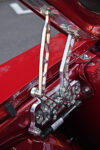 Close-up shot of a custom polished billet aluminum aftermarket hood hinge with a black gas strut installed on a candy apple red 1969 Chevy Camaro inner fender.