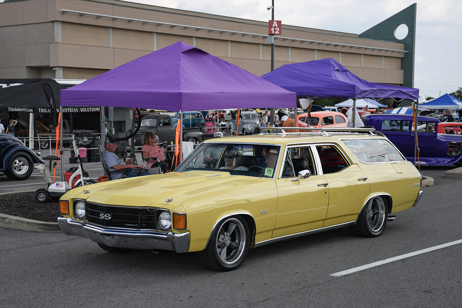 Front three-quarter profile of a custom pastel yellow 1972 Chevrolet Chevelle SS station wagon with five-spoke alloy wheels parked under a canopy.