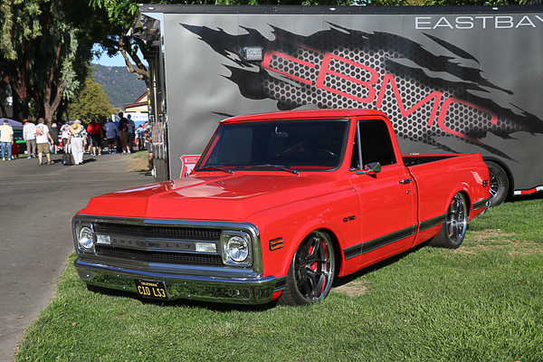 Front three-quarter view of a lowered bright red 1969–1970 Chevrolet C10 LS3 pickup truck parked on the grass at the Goodguys Pleasanton West Coast Nationals.