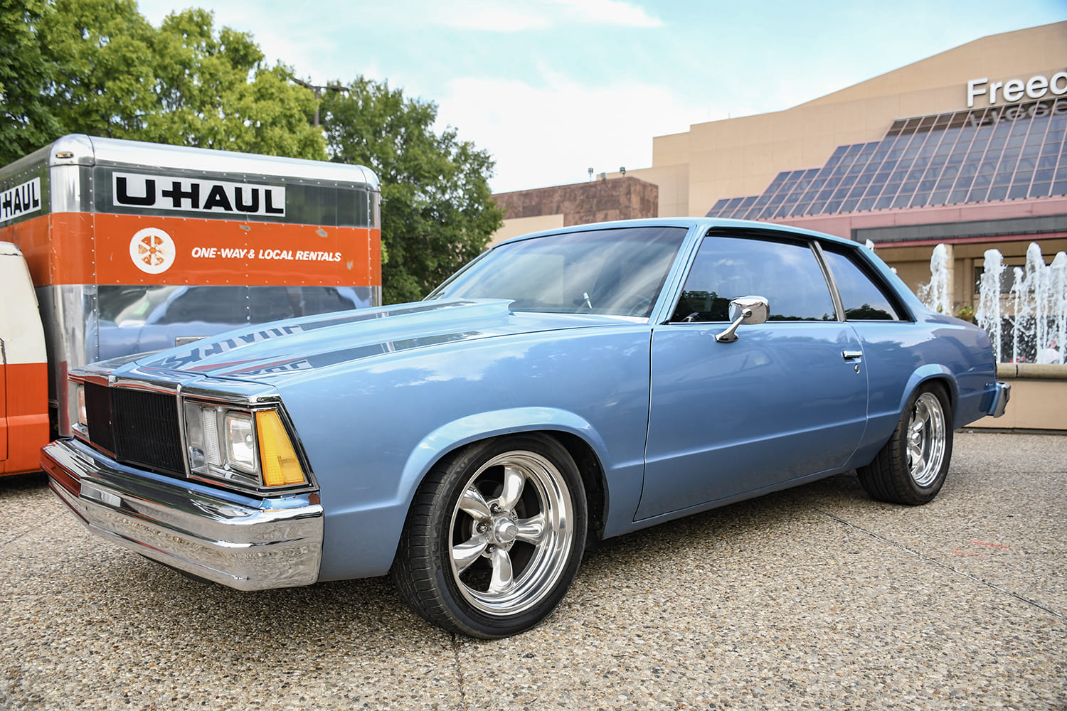 Front three-quarter low angle of a custom light metallic blue Chevy Muscle Car Malibu two-door coupe with a cowl induction hood.