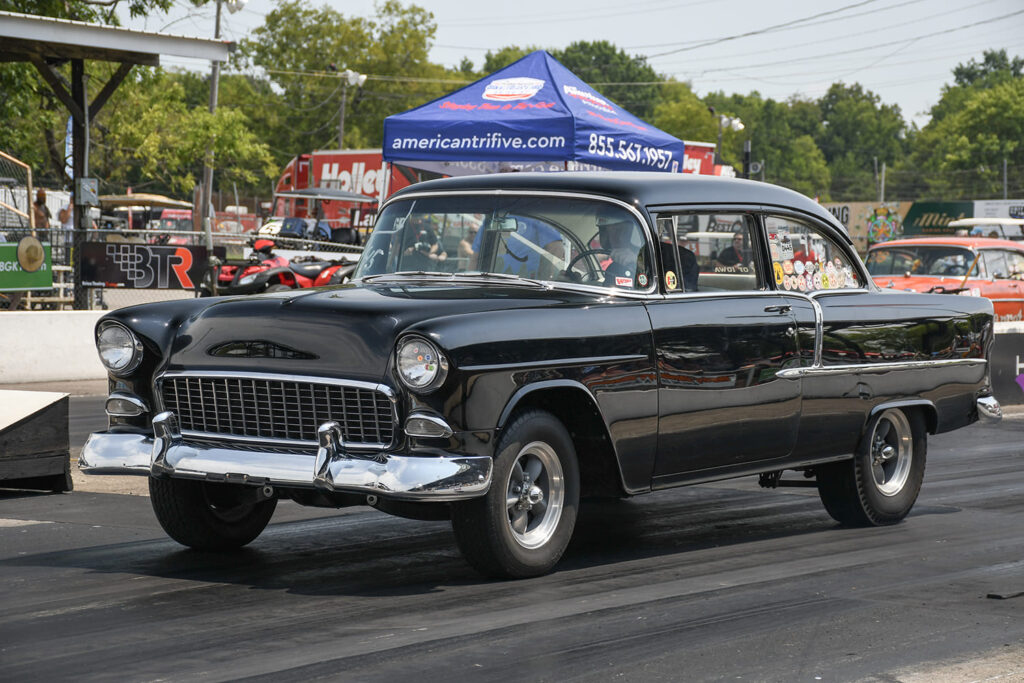 Front three-quarter view of a black 1955 Chevrolet two-door post sedan staging on the drag strip at Beech Bend Raceway.