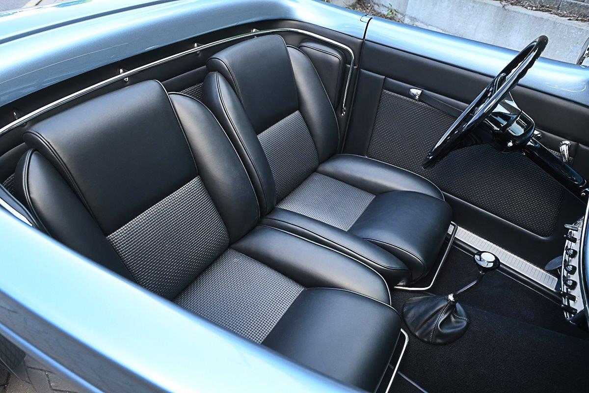 Overhead interior view of a 1933 Ford roadster featuring custom black leather bucket seats with patterned cloth inserts and floor-mounted manual shifter.