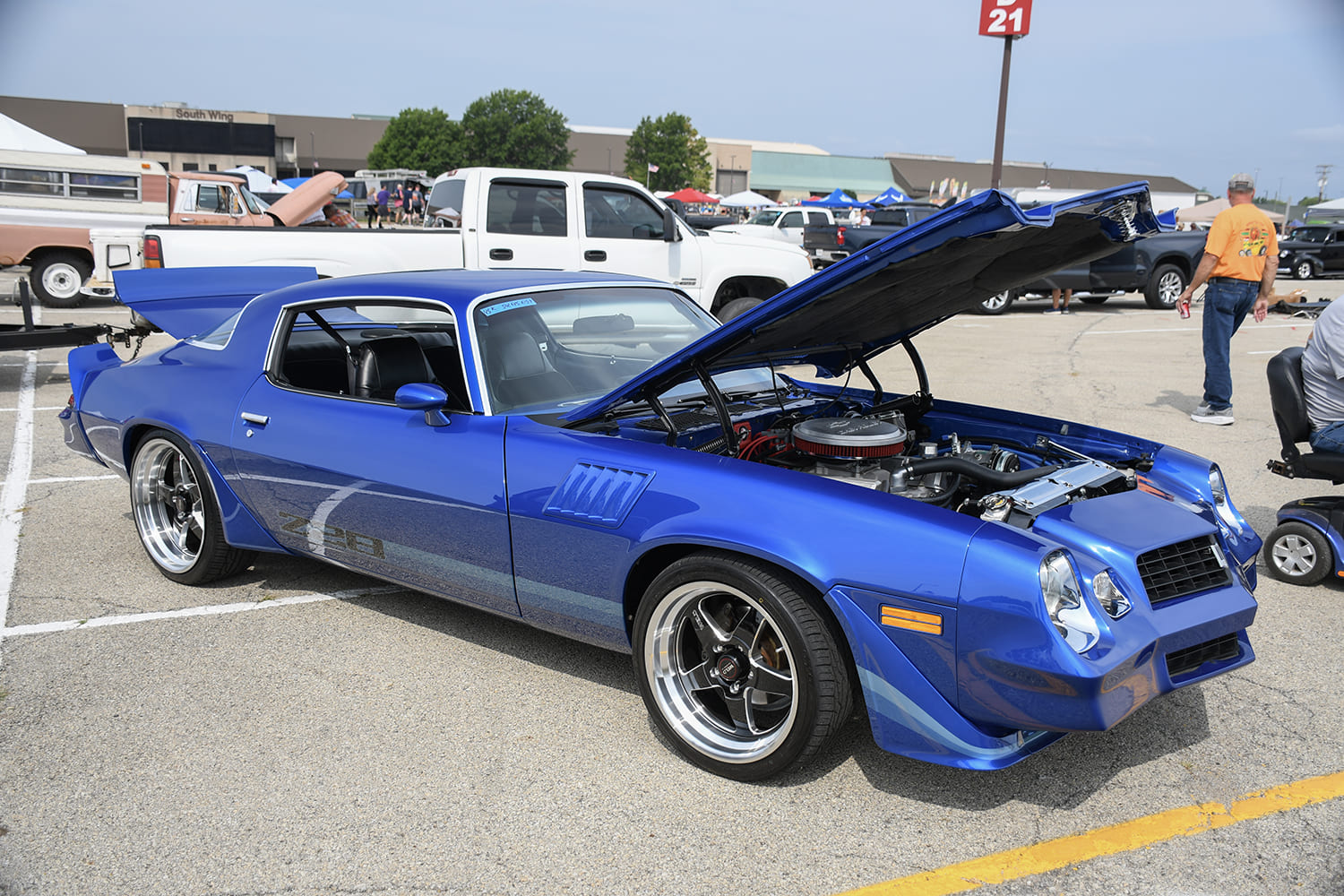 Front three-quarter view of a vivid metallic blue late-second-gen Chevy Camaro Z28 with an open hood, black-center wheels, and an oversized rear spoiler.