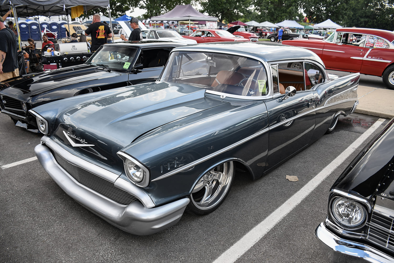 Front three-quarter low angle of a custom slate blue 1957 Chevrolet Bel Air with modern billet wheels and silver custom bumpers.