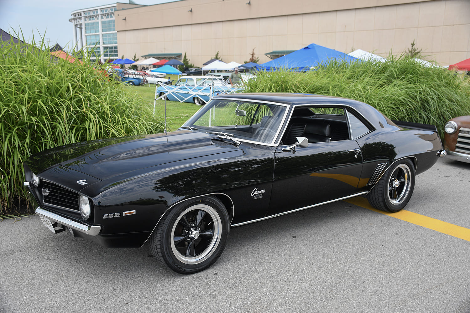 Front three-quarter view of a clean gloss black 1969 Chevrolet Camaro SS 396 muscle car with classic five-spoke wheels.