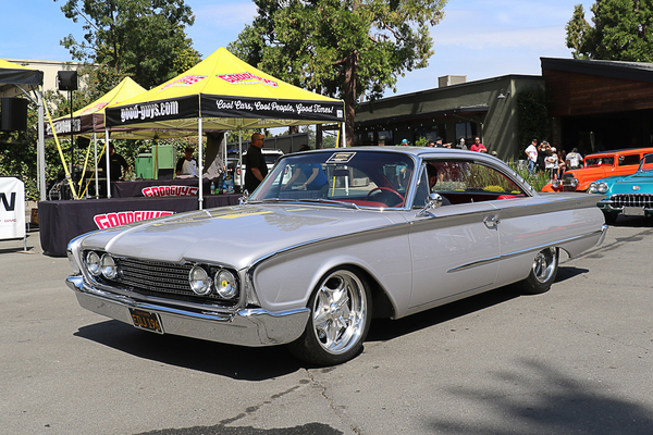 Front three-quarter view of a metallic silver 1960 Ford Starliner hardtop driving past the Goodguys tent at the Goodguys Pleasanton West Coast Nationals.