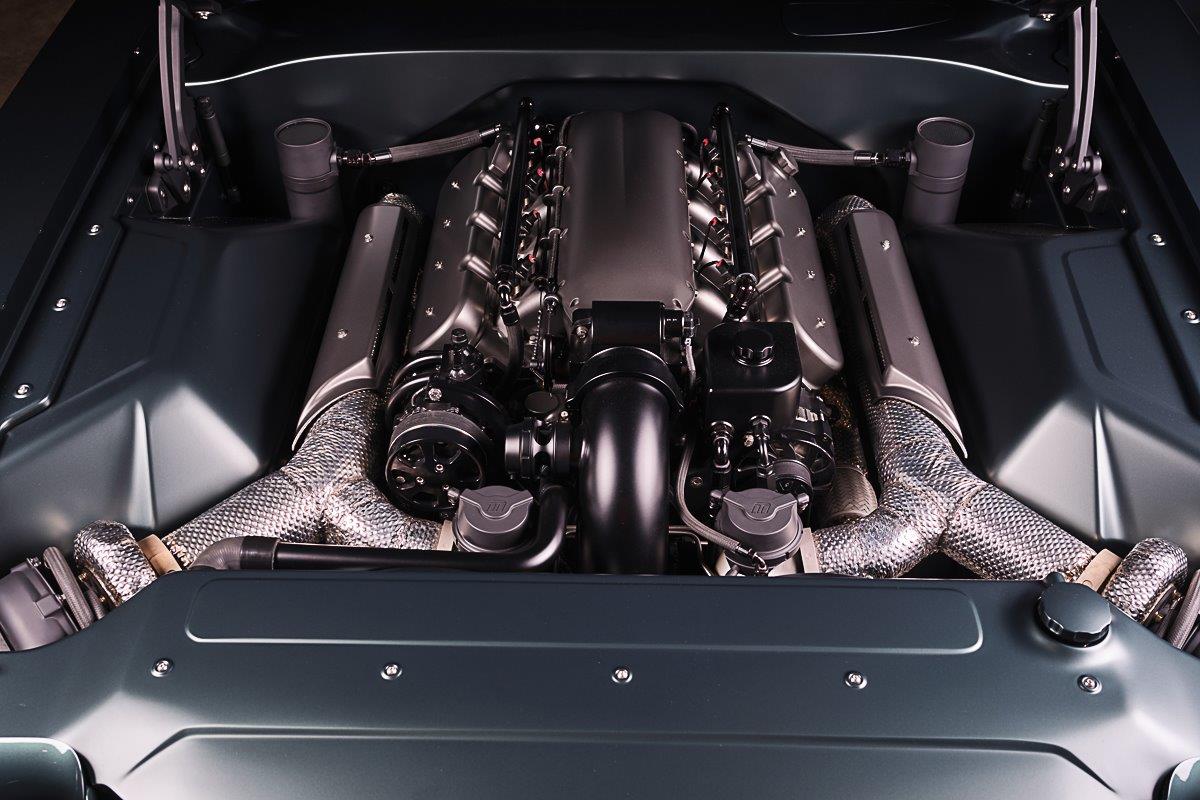 Top-down view of an ultra-clean custom engine bay featuring a twin-turbocharged V8 with heat-wrapped exhaust tubing and a matte gray fabricated intake.