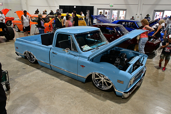 Front high-angle view of a slammed baby blue 1969–1970 Chevrolet C10 custom pickup truck with its hood open on display indoors at the Goodguys Pleasanton West Coast Nationals.