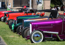 Side view lineup of traditional hot rods leading with a metallic magenta purple 1932 Ford roadster with white wall tires parked on the grass at the Goodguys Pleasanton West Coast Nationals.