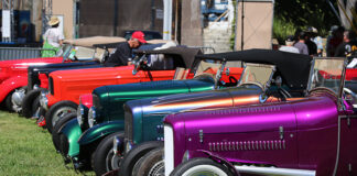 Side view lineup of traditional hot rods leading with a metallic magenta purple 1932 Ford roadster with white wall tires parked on the grass at the Goodguys Pleasanton West Coast Nationals.