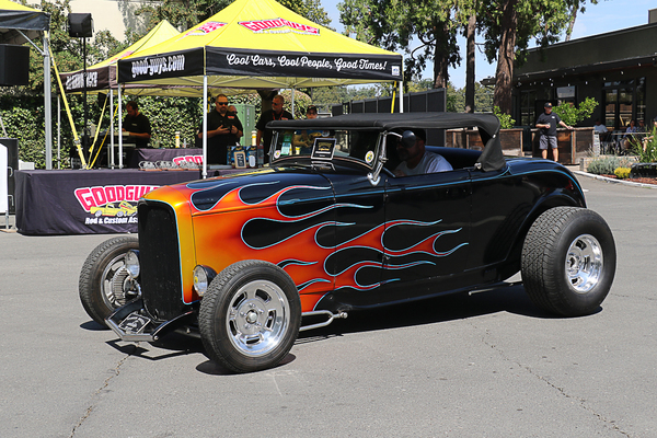 Front three-quarter view of a black 1932 Ford roadster hot rod with classic orange flames driving past the Goodguys tent at the Goodguys Pleasanton West Coast Nationals.