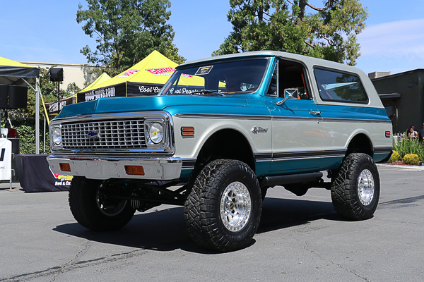 Front three-quarter view of a lifted two-tone teal and white 1971–1972 Chevrolet K5 Blazer 4x4 driving past the Goodguys tent at the Goodguys Pleasanton West Coast Nationals.