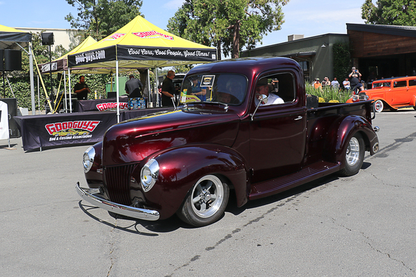 Front three-quarter view of a custom burgundy 1940 Ford pickup street rod cruising past the Goodguys tent at the Goodguys Pleasanton West Coast Nationals.