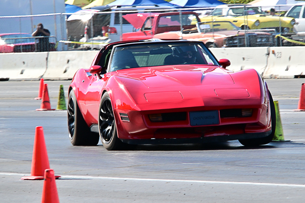 Front three-quarter view of a bright red late C3 Chevrolet Corvette racing through the autocross cone course at the Goodguys Pleasanton West Coast Nationals.