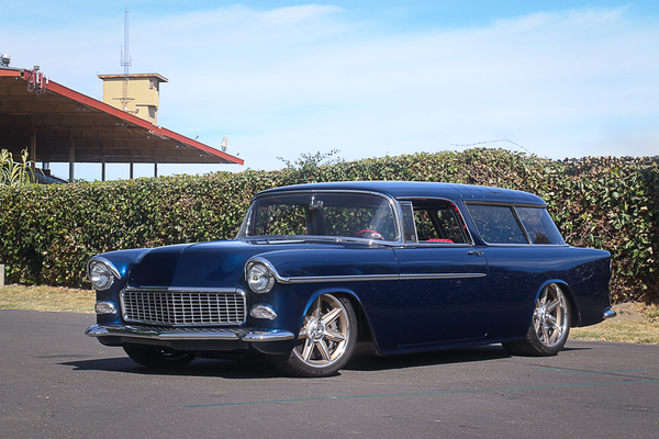 Front three-quarter view of Bryan Williams’ slammed deep metallic blue 1955 Chevrolet Nomad wagon custom rod parked outdoors at the Goodguys Pleasanton West Coast Nationals.