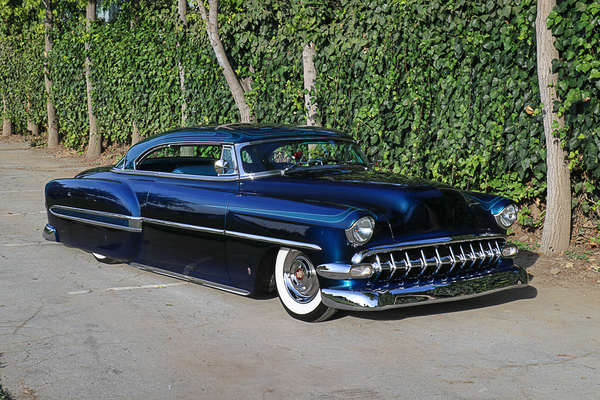 Front three-quarter view of Homer Diaz’s bagged deep metallic blue 1954 Chevrolet Bel Air custom hardtop with subtle pinstriping parked outdoors at the Goodguys Pleasanton West Coast Nationals.