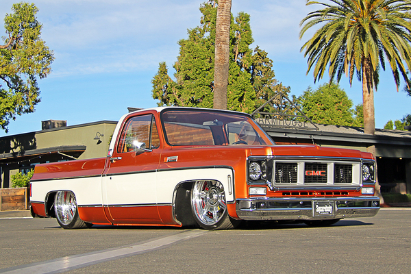 Front three-quarter low-angle view of Scott Hackbarth’s slammed two-tone metallic copper and white 1973 GMC Sierra pickup truck at the Goodguys Pleasanton West Coast Nationals.