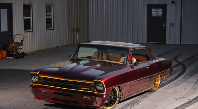 Pro Touring Style 1967 Nova Restomod Custom 1967 Chevrolet Chevy II Nova restomod in deep candy apple red paint with gold accents and custom wheels parked outside a workshop.