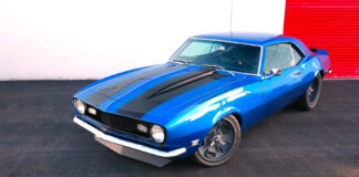 High-angle front three-quarter view of a bright blue 1968 Chevrolet Camaro SS restomod with black cowl stripes and custom gray wheels.