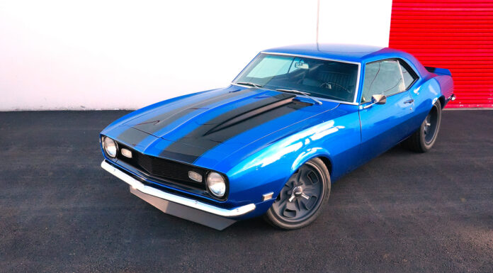 High-angle front three-quarter view of a bright blue 1968 Chevrolet Camaro SS restomod with black cowl stripes and custom gray wheels.