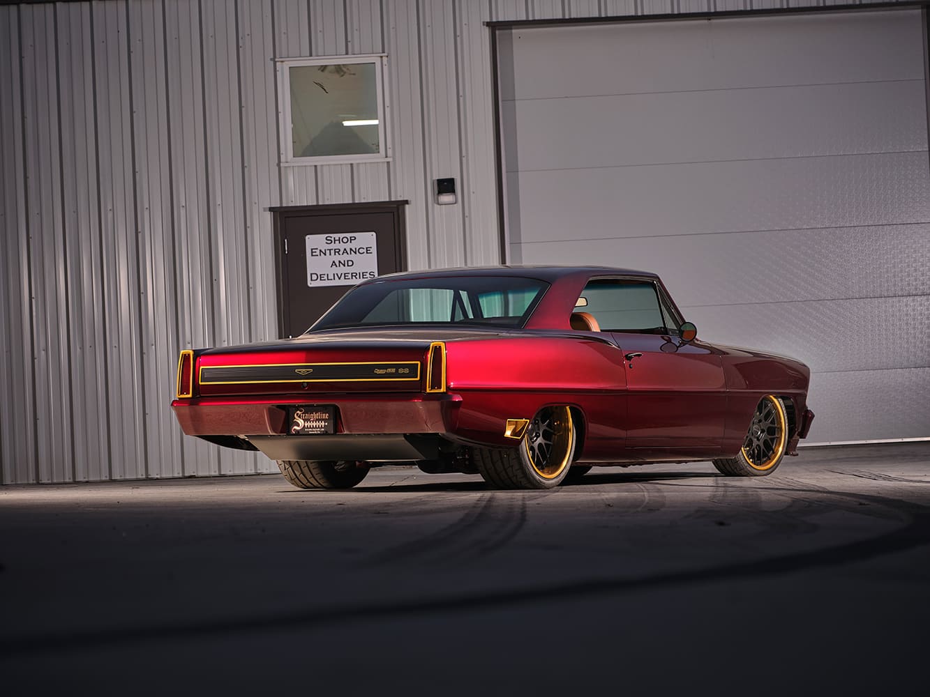 Low rear-angle view highlighting the aggressive wide-tire stance, gold body trim, and custom rear valance on the 1967 Chevy Nova Casanova.