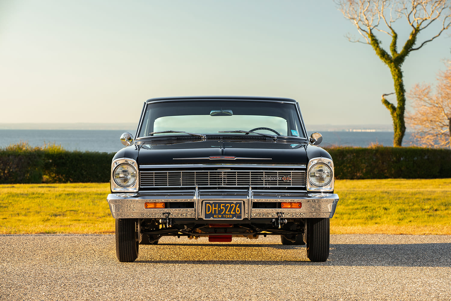 Direct head-on view of the chrome grille, Chevy II SS badge, dual round headlights, and front bumper on a black 1966 Nova.