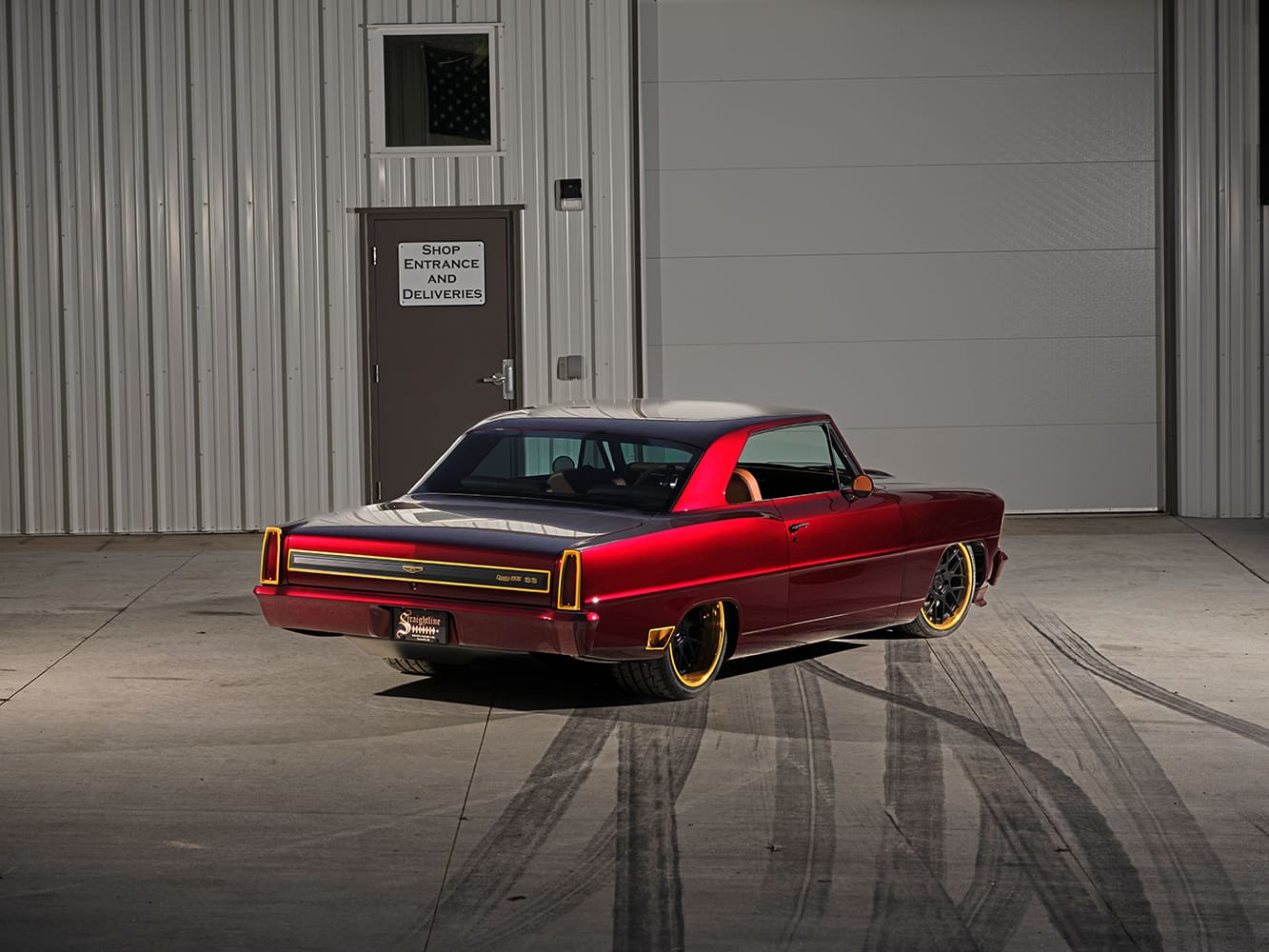 Rear three-quarter view of a custom candy red 1967 Chevy II Nova SS restomod showing modern vertical flush LED taillights and side-exit exhaust tips.