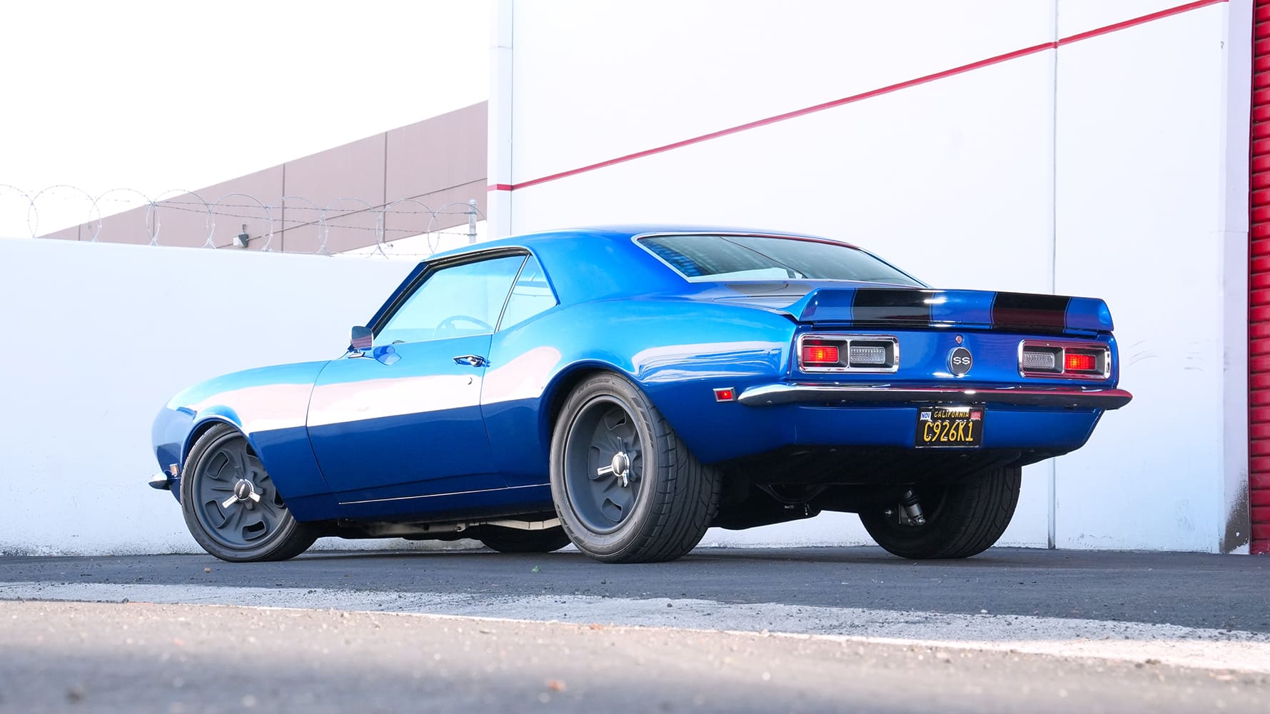 Low rear three-quarter shot displaying the ducktail rear spoiler, SS trunk badge, wide performance rear tires, and chrome bumper on a 1968 Camaro.
