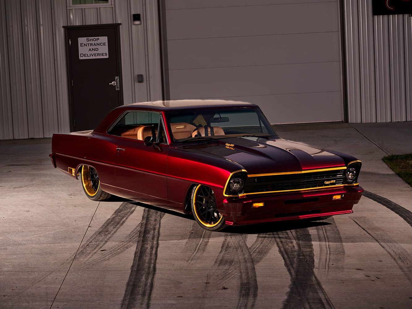 Front three-quarter exterior angle of a lowered 1967 Chevy Nova restomod with gold grille accents, custom headlights, and black wheels with gold lips.