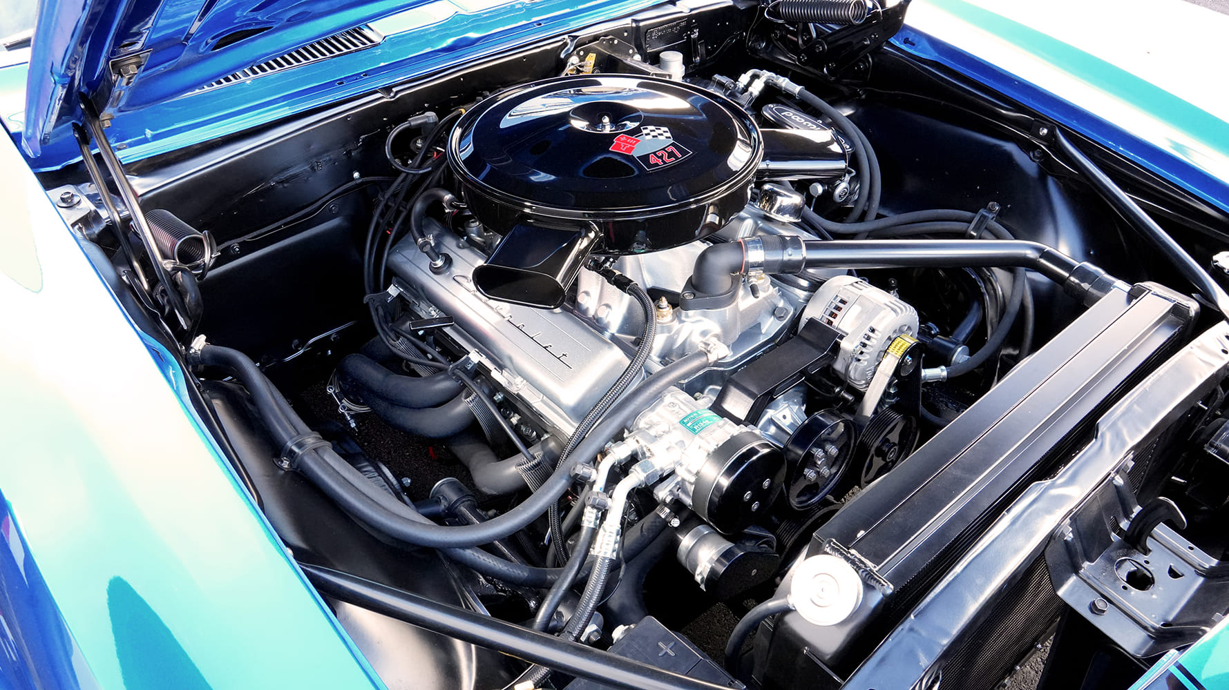 Overhead view of an immaculate 427 cubic-inch V8 engine bay in a 1968 Camaro featuring a gloss black air cleaner, polished intake, and billet serpentine drive.