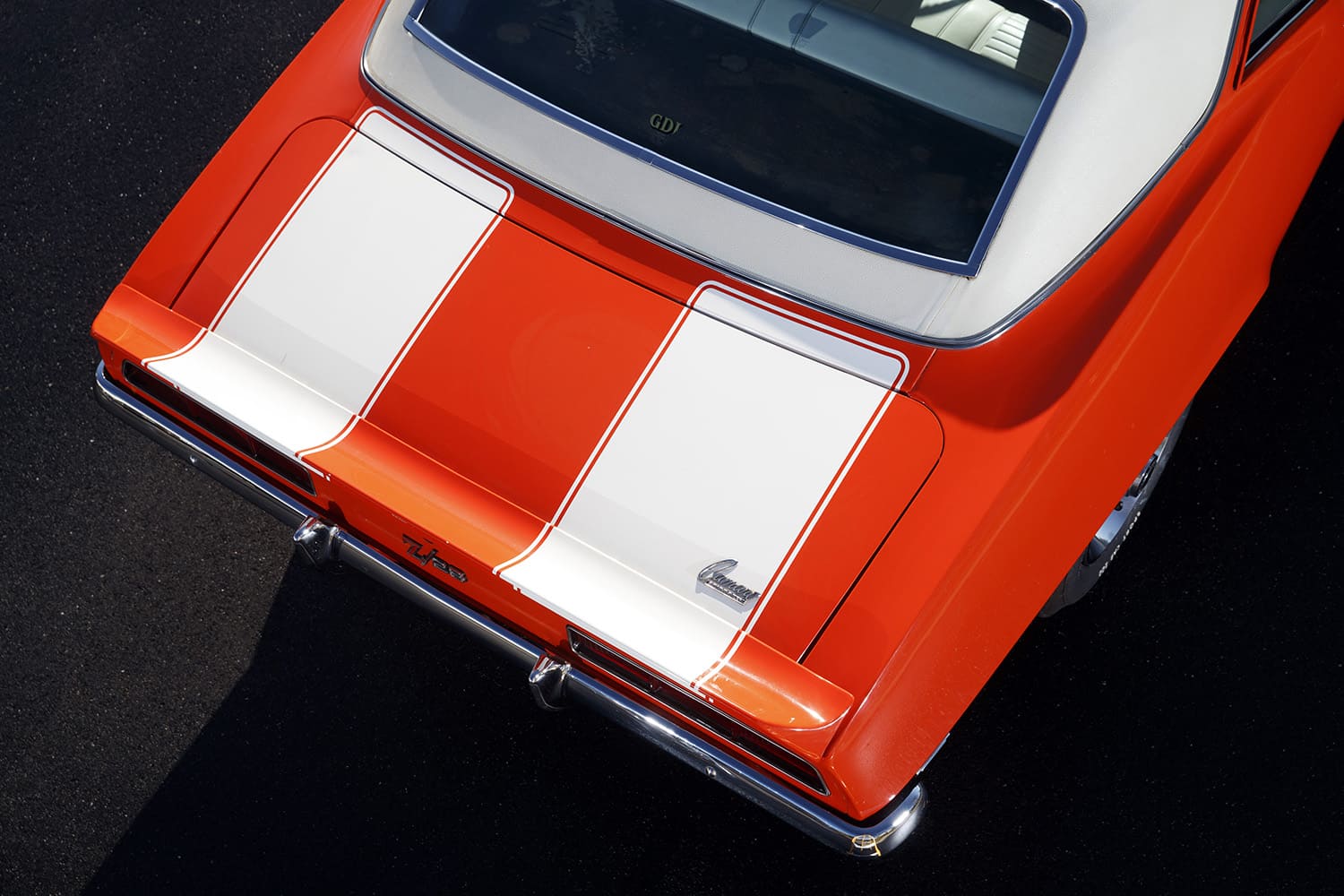 High close-up angle over the trunk lid and rear spoiler showing the white racing stripes, chrome rear bumper, and original Z/28 emblem.