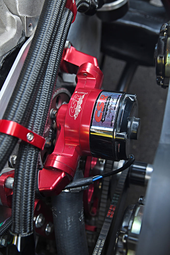 Close-up view of a red anodized CSR Performance electric water pump mounted on a high-performance big-block Chevy engine.