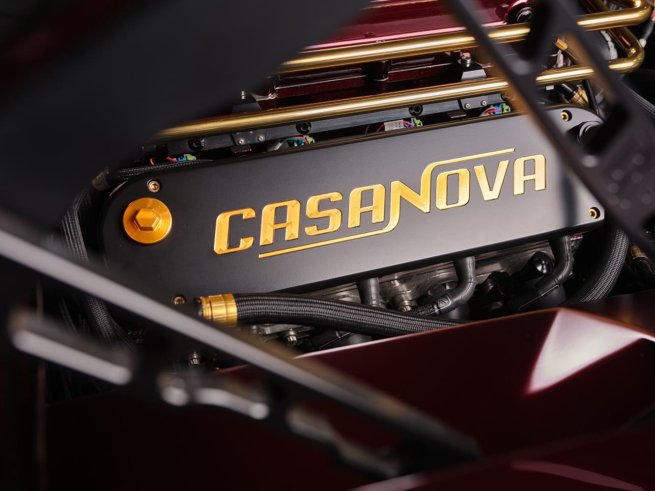 Matte black valve cover with gold engraved Casanova lettering and gold AN fitting on a 1967 Chevy Nova custom build.