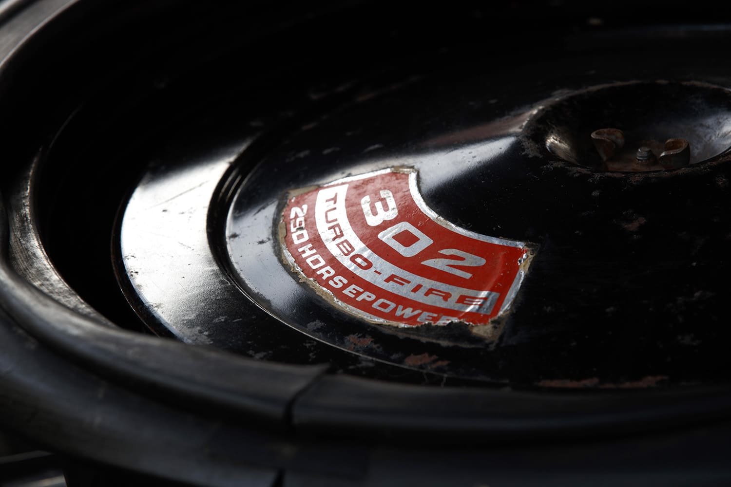 Macro view of the weathered factory red and white decal on the black cowl induction air cleaner lid reading "302 Turbo-Fire 290 Horsepower."