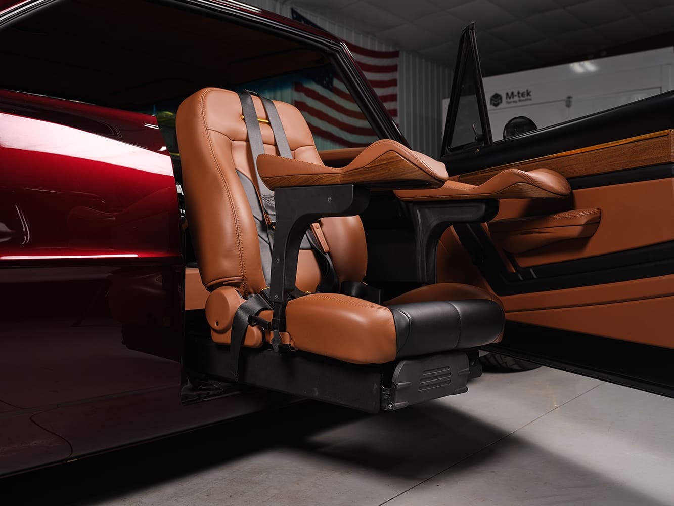 Custom power swivel accessibility bucket seat with safety harness deployed outward through the passenger door of a 1967 Chevy Nova restomod.