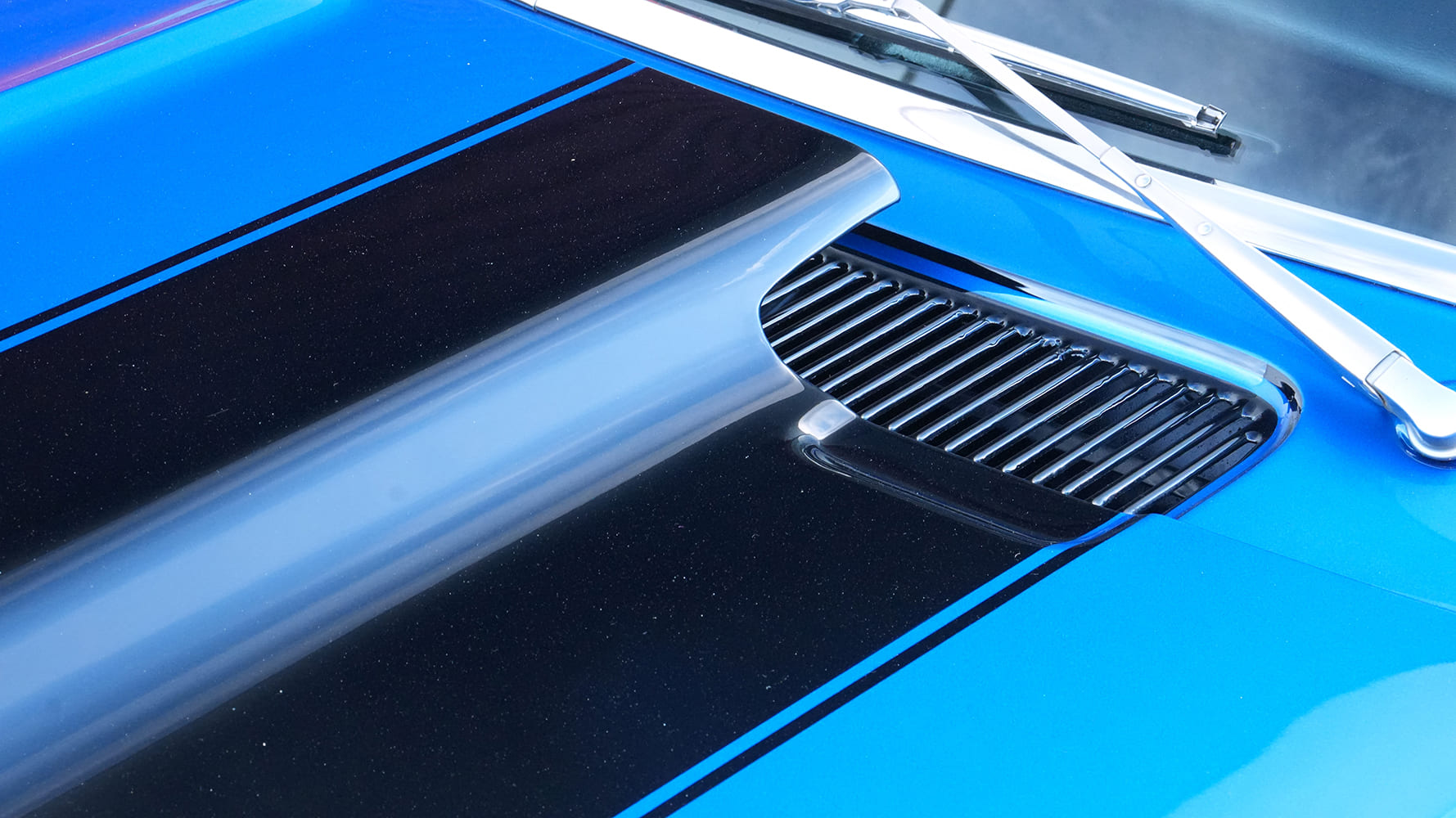 Close-up of the black center stripe, raised cowl induction hood scoop, and chrome cowl ventilation louvers on a 1968 Camaro.