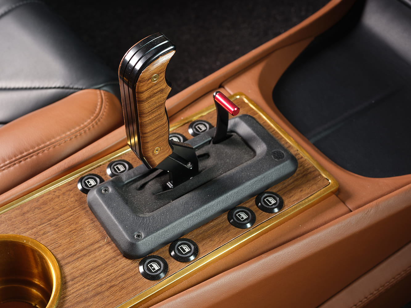 High-performance pistol-grip floor shifter with woodgrain trim, lockout lever, and power window buttons mounted on a custom leather console.