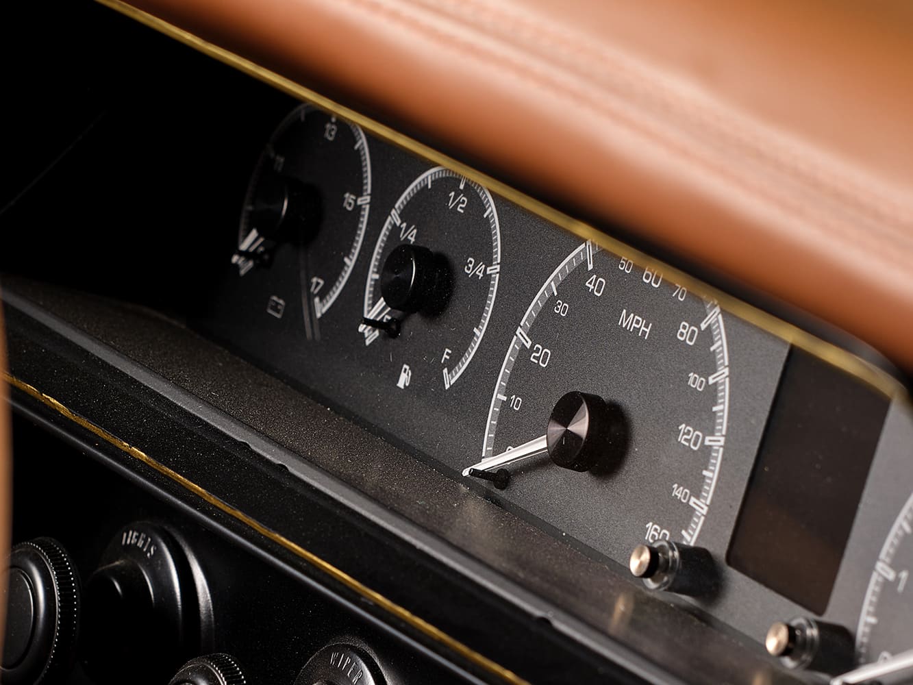 Detail view of the custom matte black analog gauge cluster and speedometer in the dash of a 1967 Chevy Nova restomod.