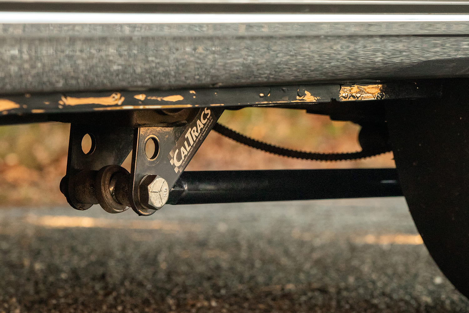 Underside view of black CalTracs traction bars mounted to the rear leaf spring suspension on a 1966 Chevy Nova drag car.