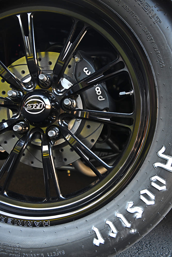 Macro shot of a gloss black RC Components front drag wheel wrapped in a Hoosier front-runner tire with a Wilwood disc brake caliper visible.