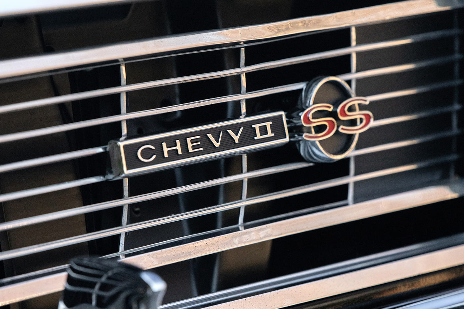 Macro close-up of the original-style horizontal chrome grille bar showing the distinct Chevy II SS Super Sport script badge.